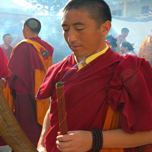 A tibetan monk holding incense in his hand.