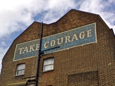 Budynek z napisem Take Courage namalowanym na ścianie.