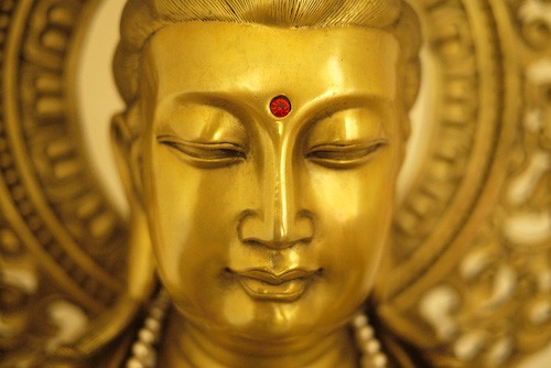 Close up on the face of a bronze Kuan Yin statue.