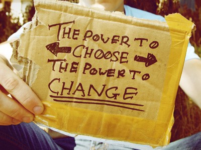 Young man holding a sign that says 'The power to choose... the power to change."