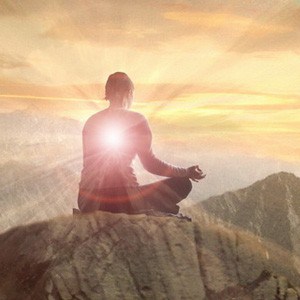 A person sitting on top of a moutain, meditating.