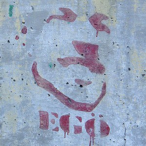 ఒక వ్యక్తి యొక్క ముఖం మరియు 'EGO' అనే పదం గోడపై పెయింట్ చేయబడింది.
