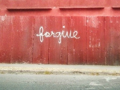 The word 'forgive' spray painted on a red wall.