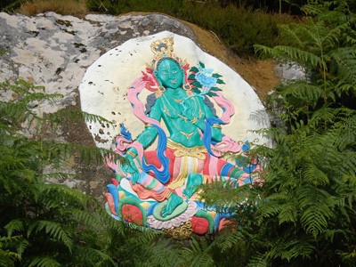 A painting of the green tara on a rock