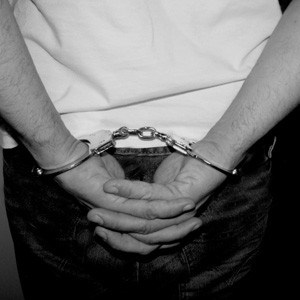 A man's handcuffed hands behind his back.