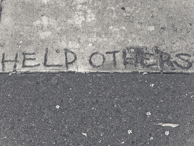 The words 'Help others' written on a concrete sidewalk.