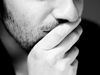 A man using his hand shielding his mouth, in deep thinking.