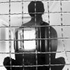 Transparent silhouette of man meditating behind prison bars.
