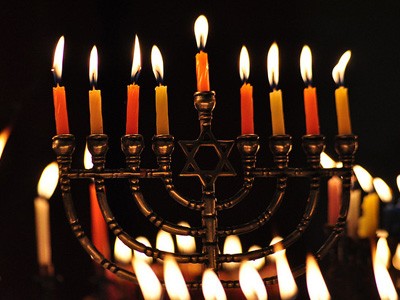 A menorah with lit candles against a dark background.