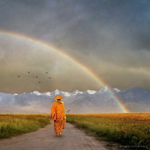 a monk walking on a road with a rainbow appearing in front of him.