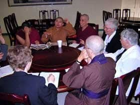 A group of nuns from various religions sitting at a table, talking.