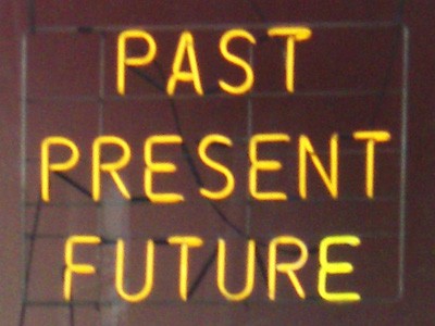 The words past, present, and future in yellow neon.