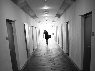 A man carrying a bag walking out in a passageway.