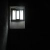 Prison cell window that has light pentrating through, surroundings are in darkness.