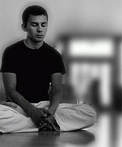 Black and white image of a young man meditating.