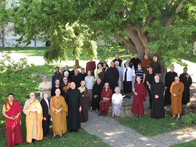 Group of monastics from various religions standing under a tree.