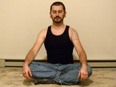 Man sitting in meditation with eyes closed.