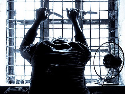 Silhouette of man holding prison bars.