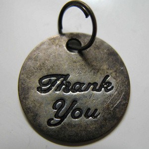 Silver medallion with the words 'Thank you' engraved on it.