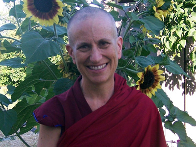 Venerable standing in front of sunflowers, smiling.