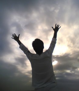 A man with both hands reaching to the sky.