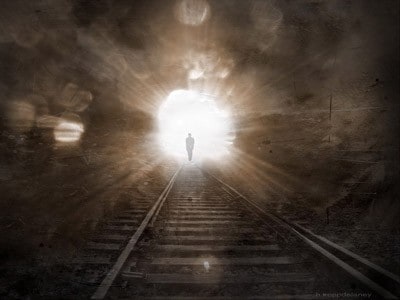 رجل يسير باتجاه ضوء قادم على رف سكة حديد.