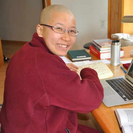 قوي دامشو يبتسم ، مع كتاب وجهاز كمبيوتر محمول.