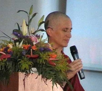Venerable Chodron with eyes closed, holding a microphone.