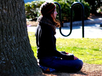 Young woman meditating outside under a tree.