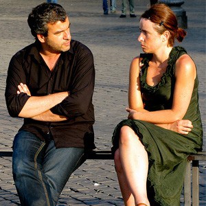 A man and woman sitting on a bench, arguing.