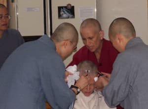 Venerable and two other monastics shaving Jan's head.