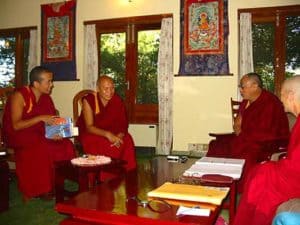 Venerable sitting with His Holiness the Dalai Lama and monks.