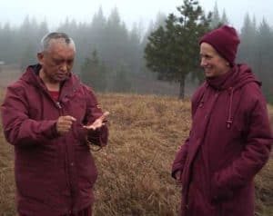 Venerable Chodron and Lama Zopa Rinpoche, standing outside, in conversation.