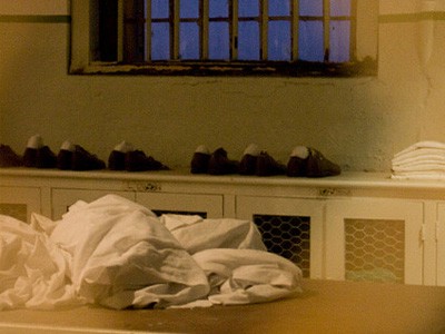 Shoes and towels on a prison shower table.
