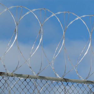 Blue sky behind prison razor wire.