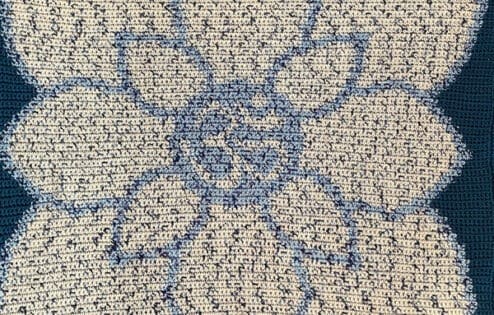 A hand-made blue blanket with a white lotus in the center.