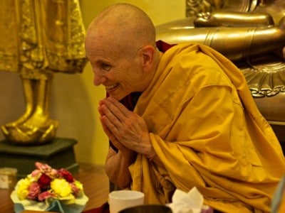 Venerable Thubten Chodron bowing forward and smiling happily.