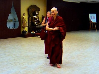 Venerable Thubten Chodron walking and smiling happily, Venerable Damcho walking behind also smiling.