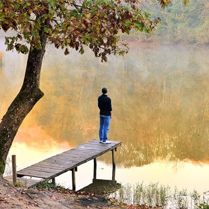 Man standing on dock of lake.