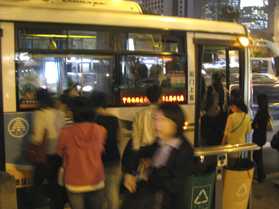 Crowd of people witing to board a bus.