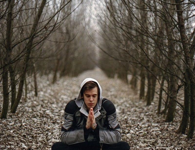 młody człowiek medytujący w lesie