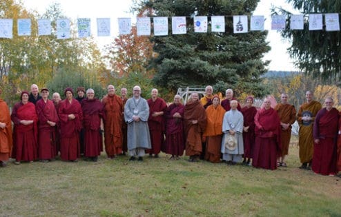 Grupa zakonników stojących pod flagami modlitewnymi.