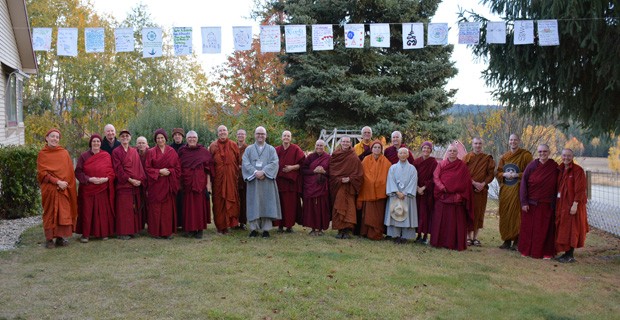 Group of monastics standing under prayer flags.