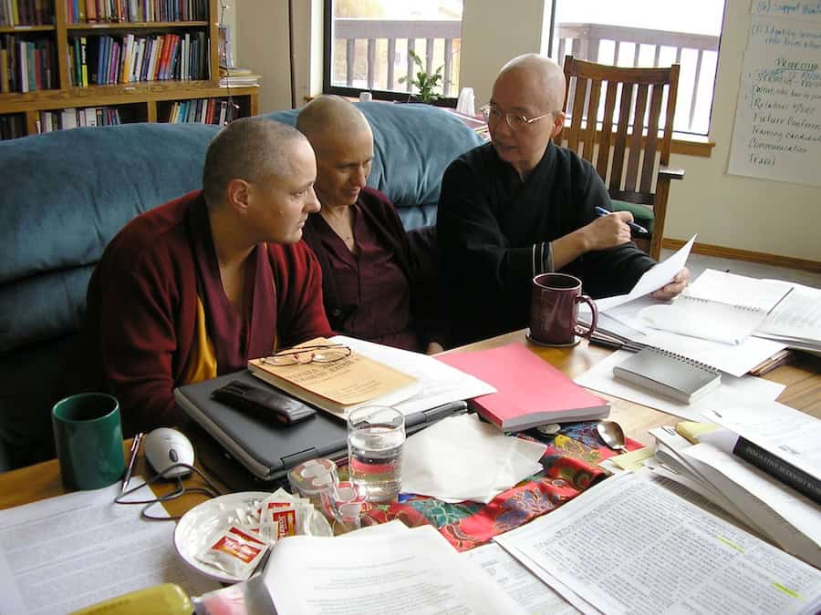 Venerable Jampa Tsedroen, Venerable Thubten Chodron, and Venerable Heng Ching sit at a table filled with research materials.