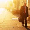 Man in business suit and carrying briefcase, walking at sunset.