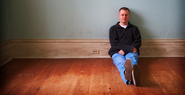Man sitting on floor, looking sad.