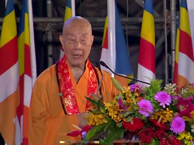 Venerable Master Jingliang standing at a podium during the award ceremony.