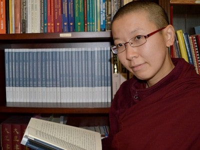 Venerable Damcho smiling and holding one of the texts.