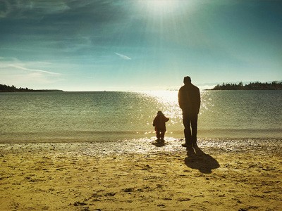 Father and son walking along a beach.