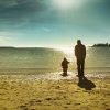 Father and son walking along a beach.